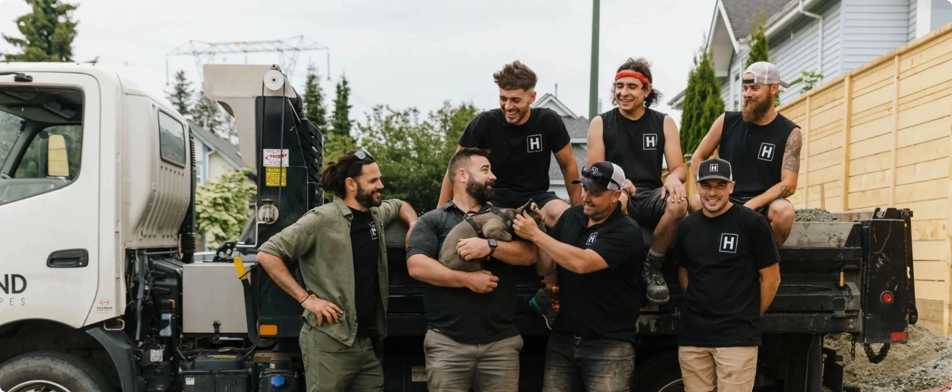 subset of Hyland's landscaping team laughing together, posing with flat-bed truck