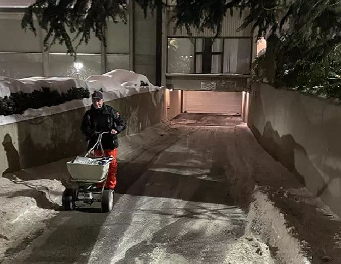 Hyland employee operating a broadcast salt spreader on driveway