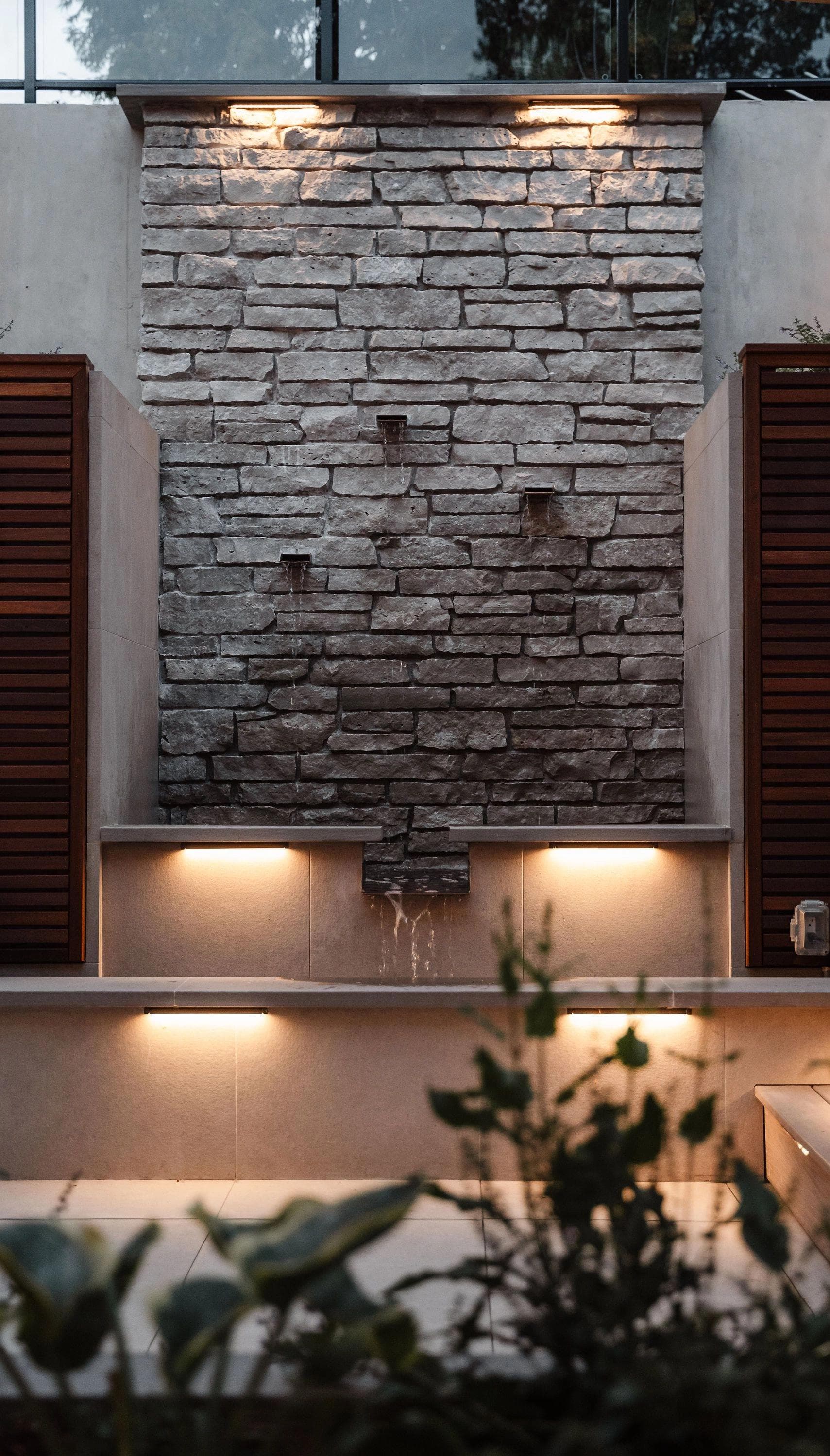 backyard retaining wall with landscape lights and water feature