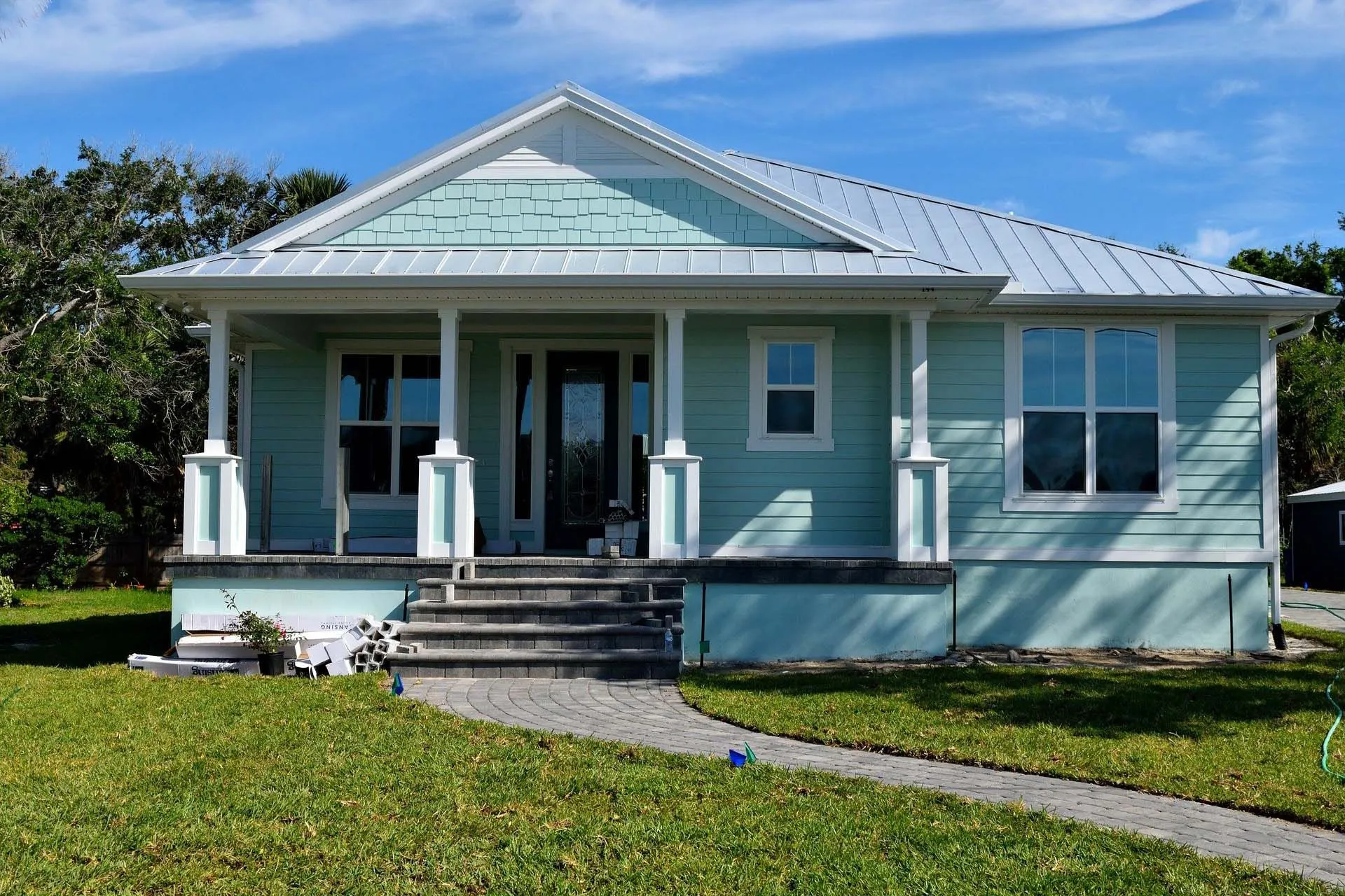 An image of a sky-blue-painted house, its lawn and a pathway