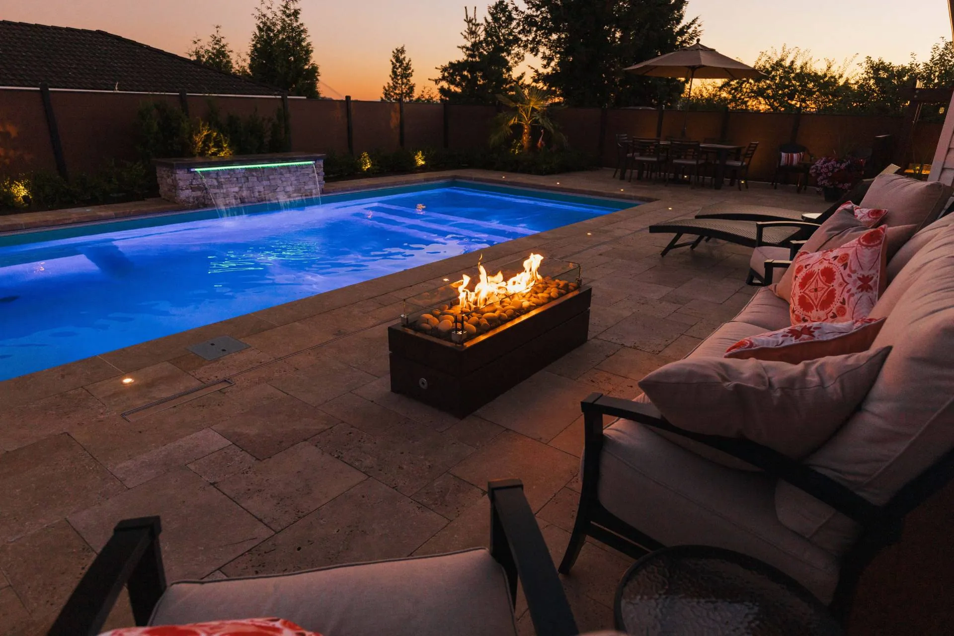 Image of an outdoor pool with an outdoor fireplace and several chairs