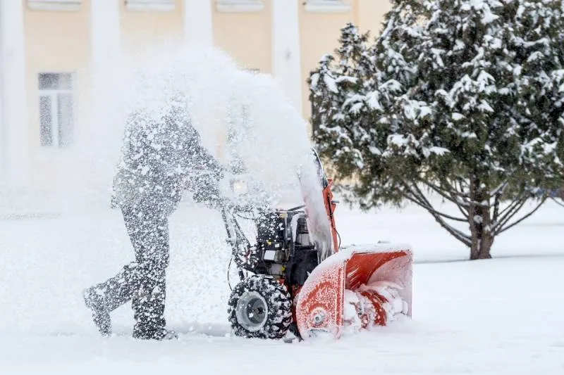 An image of a man removing snow using a machine